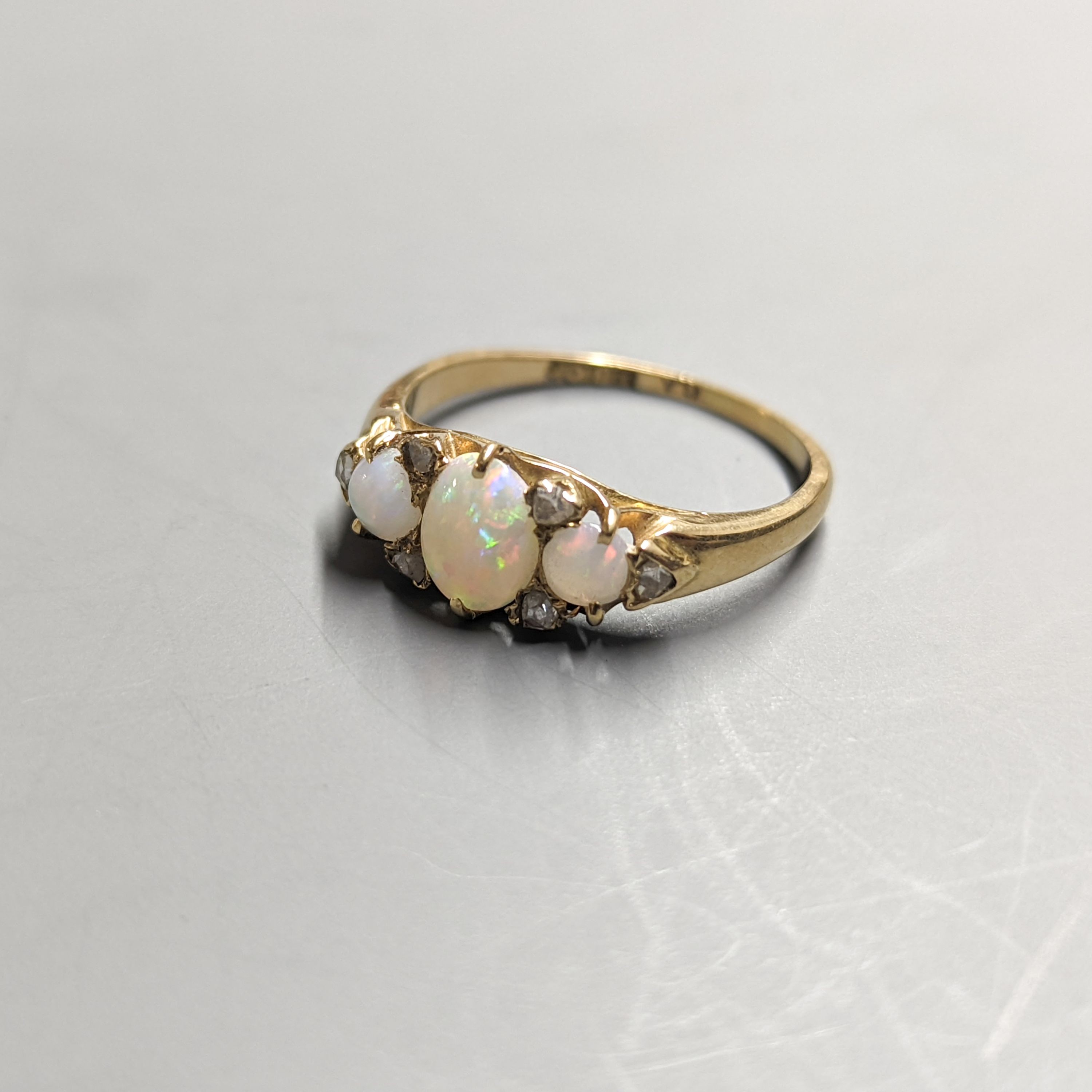 An early 20th century 18ct and three stone white opal set ring, with diamond chip spacers, size Q/R, gross 3.7 grams.
